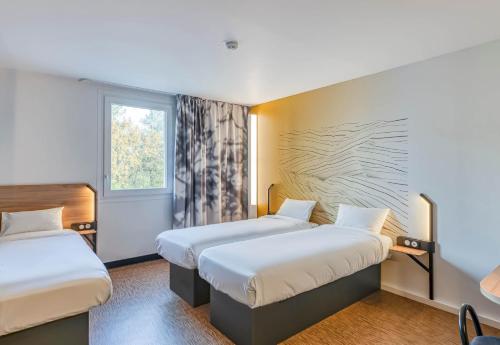 ein Hotelzimmer mit zwei Betten und einem Fenster in der Unterkunft B&B HOTEL Bordeaux Saint André de Cubzac in Saint-André-de-Cubzac