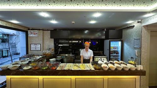 a man standing behind a counter in a kitchen with food at Morava Hotel in Istanbul