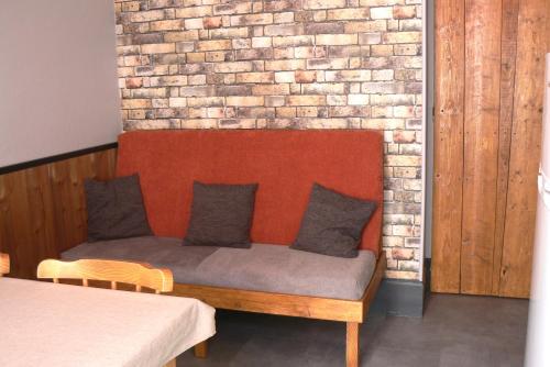 un banc avec des oreillers assis devant un mur de briques dans l'établissement La Coudraie Villa des Familles, à La Bourboule