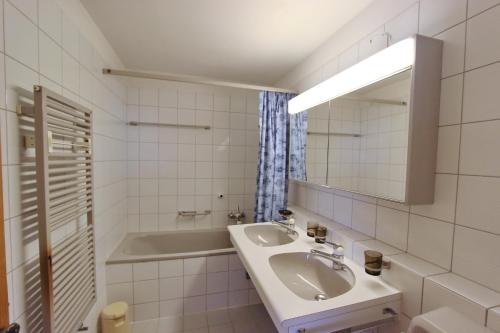 a white bathroom with a sink and a tub at Apartment Cign OG in Celerina