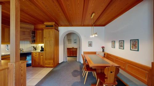 a kitchen with a wooden table and wooden ceilings at Apartment Belvair 31 in Zuoz
