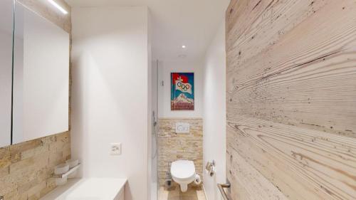 ein Bad mit einem WC und einer Holzwand in der Unterkunft Apartment Sungold in St. Moritz