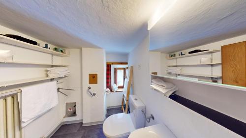 a white bathroom with a toilet and a sink at Apartment Seraina in La Punt-Chamues-ch
