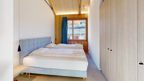 ein kleines Schlafzimmer mit einem Bett und einem Fenster in der Unterkunft Apartment Sella Nouva in Pontresina