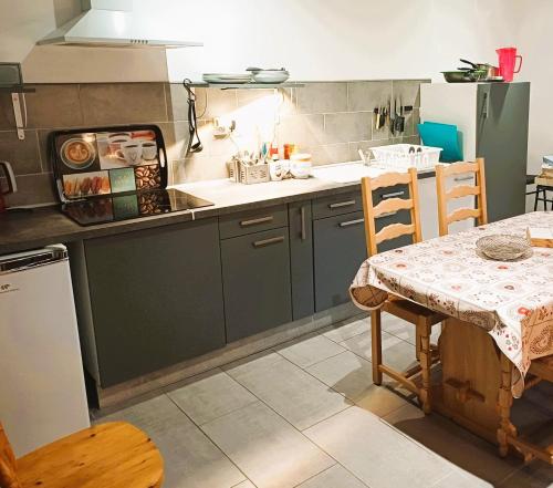 a kitchen with green cabinets and a table and a table and chairs at Gîtes Estives d'Arrens in Arrens-Marsous