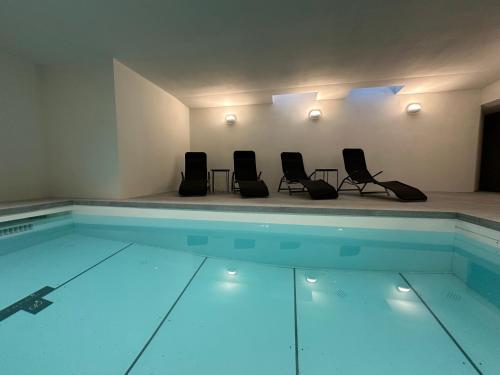 a swimming pool with four chairs in a room at Chesa Unica - Historica in Zuoz
