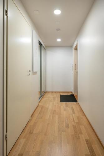 an empty hallway with white walls and wood floors at Transit Apartments HEL Airport in Vantaa