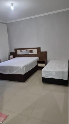 two beds in a room with white floors at Casa com piscina e lazer em SBC SP in São Bernardo do Campo