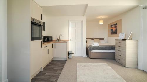 a bedroom with a bed and a dresser and a kitchen at YSS The Church 2 Apartments in Redcar