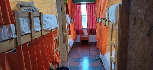 a hallway of a room with bunk beds with orange curtains at Krusty Hostel B&B in Huaraz