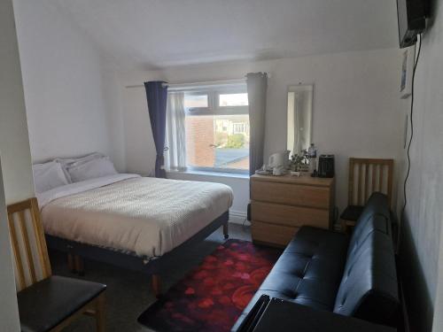 een slaapkamer met een bed, een bank en een raam bij Pinnacle Hotel & Suites formerly Jean Martyn Hotel Near Central Blackpool, Near Beach & Attractions in Blackpool
