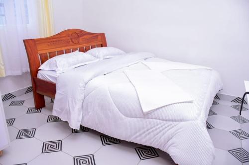 a bed with white blankets and pillows on a floor at The White House apartments in Libwezi