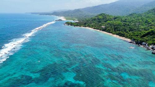 an aerial view of a beach with turquoise water at Colibri Parque Tayrona Dentro del Parque Nacional Tayrona in El Zaino