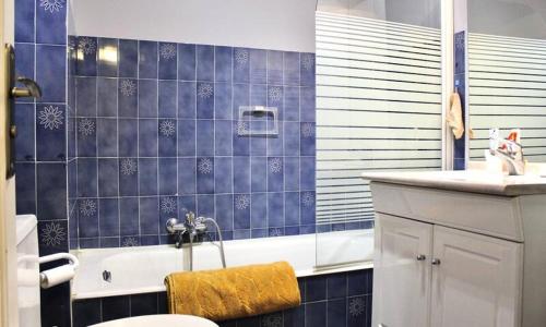 La salle de bains est pourvue de carrelage bleu, d'une baignoire et d'un lavabo. dans l'établissement Le Pêcheur, à Cagnes-sur-Mer