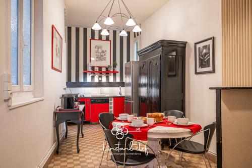 Il comprend une cuisine avec une table et des chaises rouges ainsi qu'une cuisine équipée d'un réfrigérateur. dans l'établissement Votre cocon 5 étoiles en plein centre du Mans, au Mans