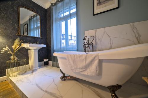 une salle de bain avec une baignoire blanche et un lavabo dans l'établissement UnSejourAMetz - Cheverny, 5 min gare, 3 chambres, à Metz