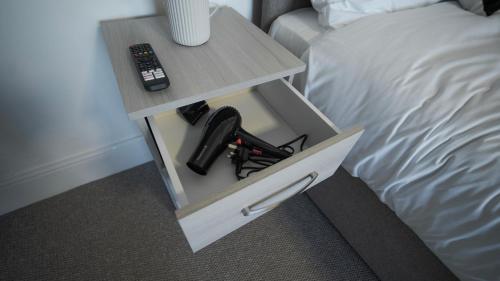 a night stand with a remote control on it next to a bed at YSS The Church 2 Apartments in Redcar