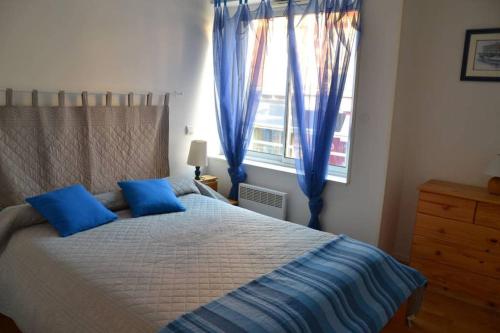 une chambre avec un lit avec des oreillers bleus et une fenêtre dans l'établissement Appartement centre d'Arcachon à 400 m de la plage, à Arcachon