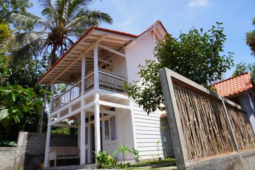 a white house with a gate and palm trees at Purwa Ijen in Banyuwangi