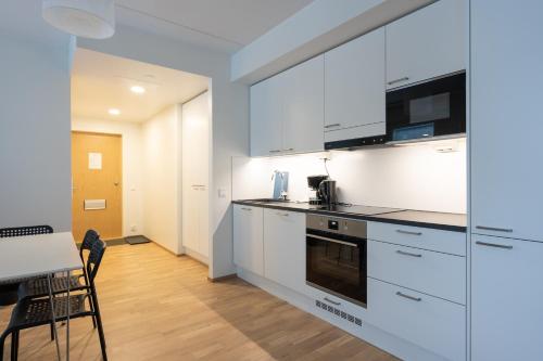 a kitchen with white cabinets and a table and chairs at Transit Apartments HEL Airport in Vantaa