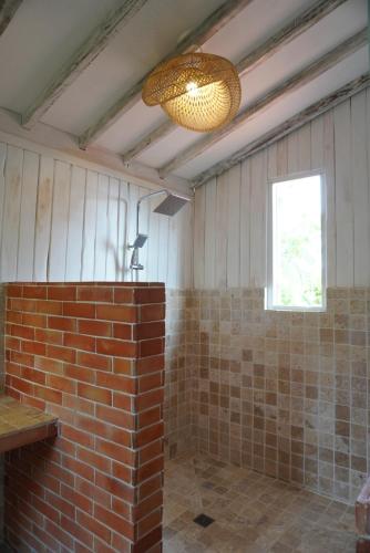 a bathroom with a brick wall and a light at Purwa Ijen in Banyuwangi
