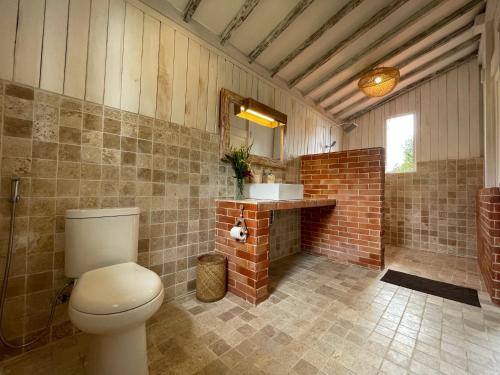 a bathroom with a toilet and a brick wall at Purwa Ijen in Banyuwangi