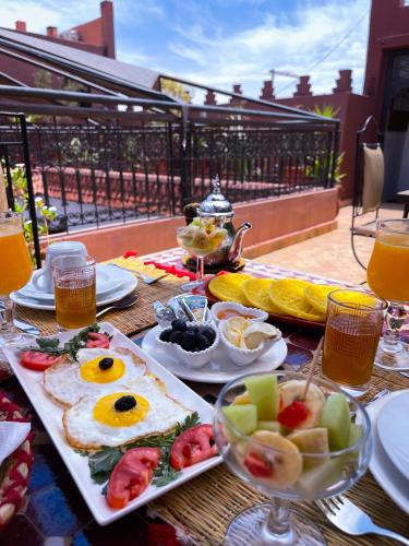une table avec des aliments et des boissons pour le petit-déjeuner sur un balcon dans l'établissement Riad La Porte Rouge By La Siredrah, à Marrakech