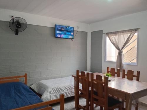 a room with a table and a bed and a television at Departamentos Los dos Pinos in San José