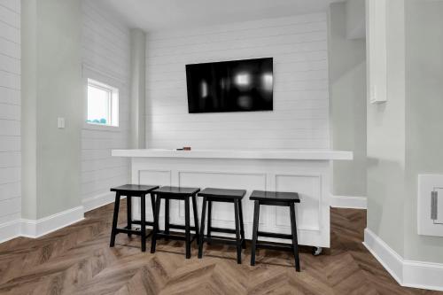 a kitchen with three bar stools and a tv on the wall at Sea Haven by Sea Scape Properties in North Topsail Beach