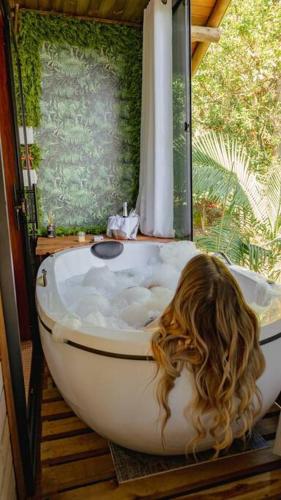 a woman with long hair in a bath tub at Morada Paraíso dos Canyons in Praia Grande
