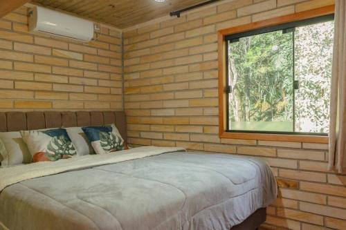 Un dormitorio con una cama en una pared de ladrillos. en Morada Paraíso dos Canyons, en Praia Grande