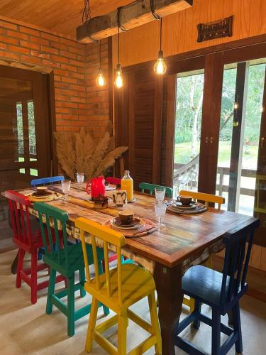 a wooden table with colorful chairs in a room at Pousada Sitio Raizes in Siderópolis