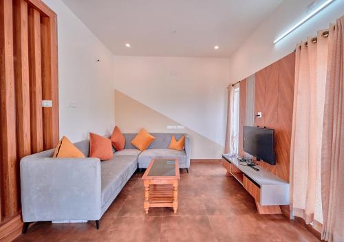 a living room with a couch and a tv at Cucuu Nest Villa Coonoor by VOYE HOMES in Coonoor