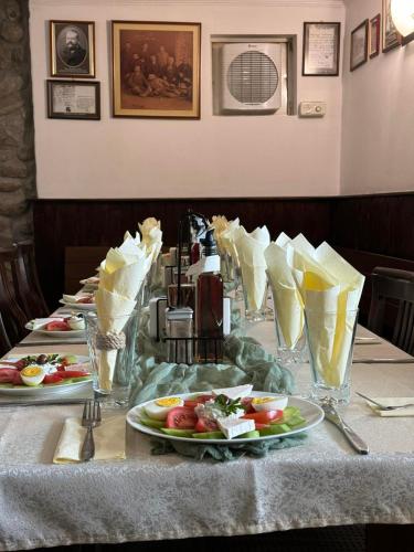 a table with plates of food and glasses on it at Семеен хотел 1876 in Apriltsi