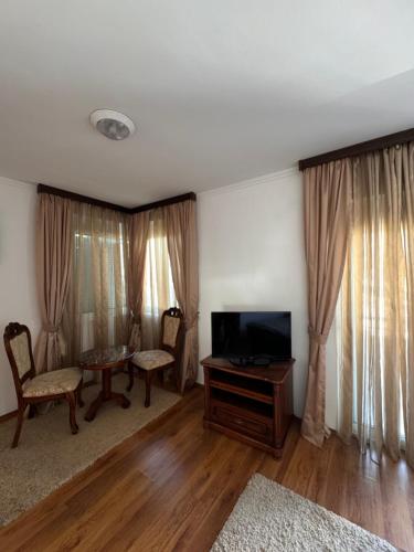 a living room with a television and a table and chairs at Villa del Mare in Dobra Voda