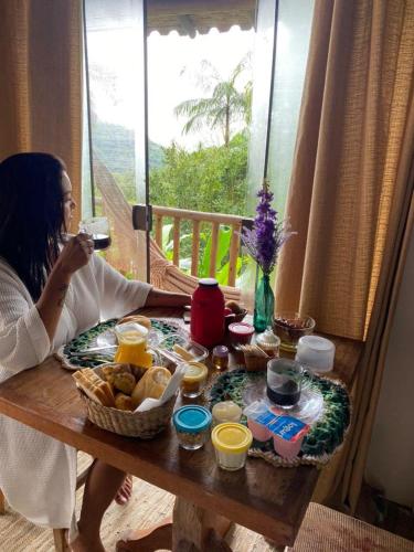 a woman sitting at a table with a plate of food at Chalés Paraty Real in Paraty