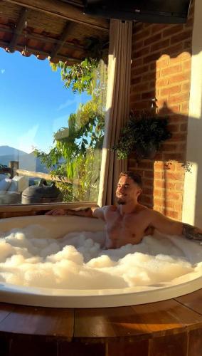 a man in a bath tub in a window at Chalés Paraty Real in Paraty