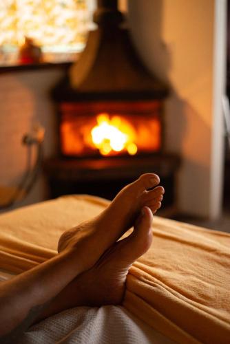 a person laying on a bed in front of a fireplace at Chalés Paraty Real in Paraty