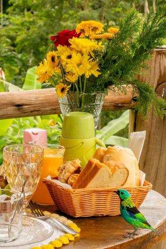 a table with a basket of bread and a vase with flowers at Chalés Paraty Real in Paraty