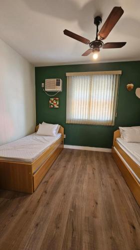 a bedroom with two beds and a ceiling fan at Casinha de Boneca em Juquey in Juquei