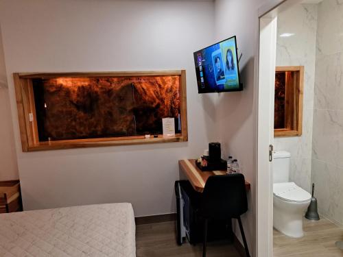 a room with a toilet and a tv on the wall at Agrafonte in Paços de Ferreira