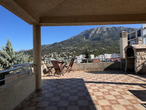 a patio with chairs and a mountain in the background at Villa del Mare in Dobra Voda