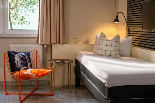 a small bedroom with a bed and a chair at SleepinRoomz Boutique Hotel in Dortmund