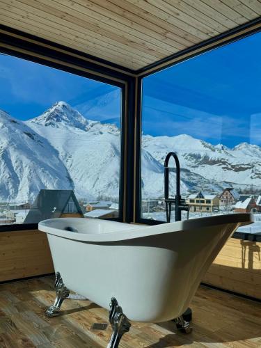 a bath tub in a room with a view of snow covered mountains at Kazbegi Inn Cottages in Stepantsminda