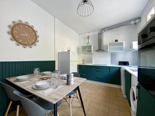 une cuisine avec une table et une horloge au mur dans l'établissement La Douceur de la Seine - 305, à Amfreville-la-Mi-Voie