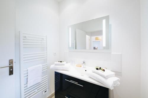 a white bathroom with a sink and a mirror at Résidence Les Terrasses de Rondinara in Bonifacio