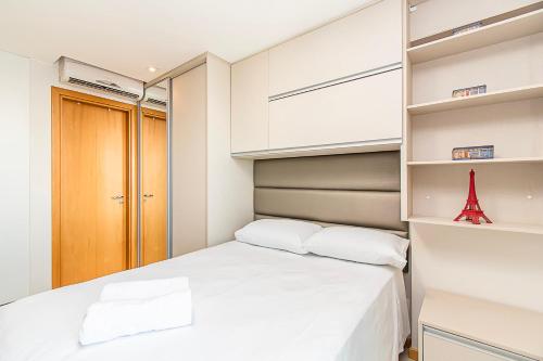 a small bedroom with a white bed and shelves at BSB STAY Premium Flats Particulares - Saint Moritz in Brasilia