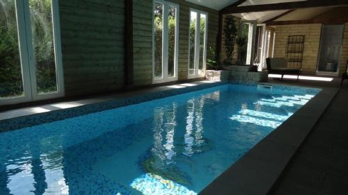 une piscine avec de l'eau bleue dans une maison dans l'établissement Le Manoir des Parcs, Piscine chauffée, à Ouilly-le-Vicomte