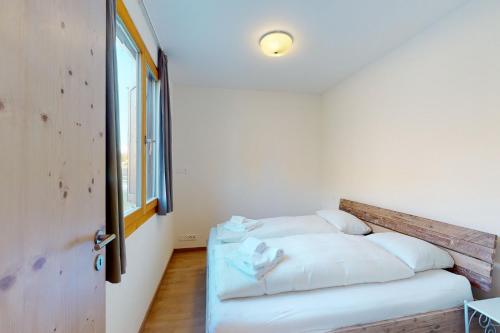 a bedroom with a bed with white sheets and a window at Apartment Blaunca in Maloja