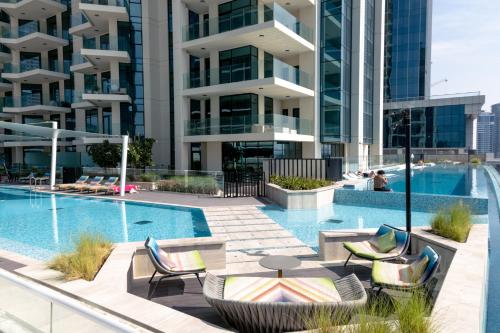 a swimming pool with chairs and a table and a building at Lusso Hometels Missoni Business Bay in Dubai